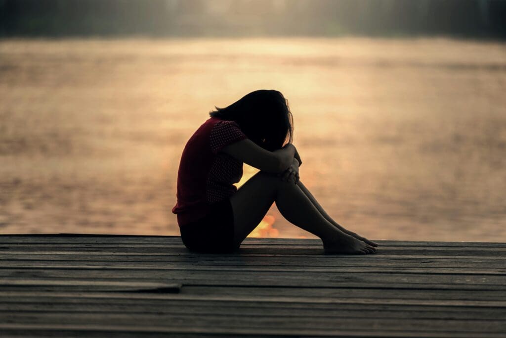 A girl who is sad by the water.